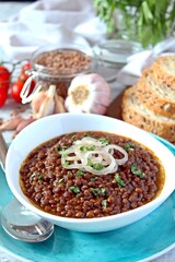 Lentils with stewed onion and tomato in a white bowl. Diet food. Top view with copy space.