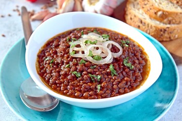 Lentils with stewed onion and tomato in a white bowl. Diet food. Top view with copy space.