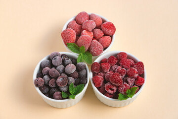 Frozen blueberries, strawberries and raspberries in bowls on a neutral background. Freezing food. Long-term storage.