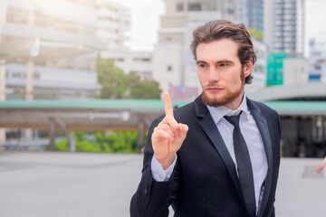 Businessman developing a new idea and pointing with finger looking away while standing outdoors. Copy space