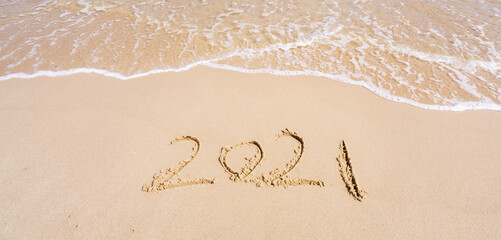 2021 year message handwritten in sand on beautiful beach background. New Years concept.