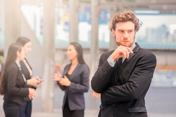 One Business Man Outdoor. Businessman posing confident and positive outdoors work occupation lifestyle with Business team standing together in the background.