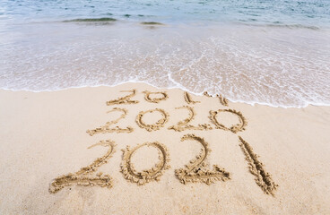 2021 and 2020 inscription written in the wet beach sand with sea water wave.