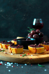 Canape or crostini with pate of olives on dark background. Top view with copy space. Healthy snack.