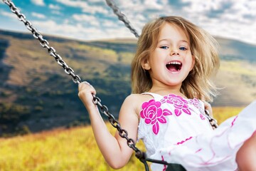 Little child blond girl having fun on a swing