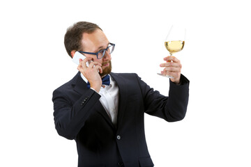 Trying white wine and talking phone. Portrait of male sommelier, wine steward or bar worker in white and black suit isolated over white background. Copyspace for ad. Concept of professional occupation
