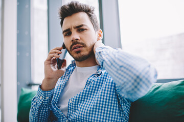 Portrait of serious confused man looking at camera while making consultancy smartphone conversation for discussing business with colleague, male feeling puzzled on received call information