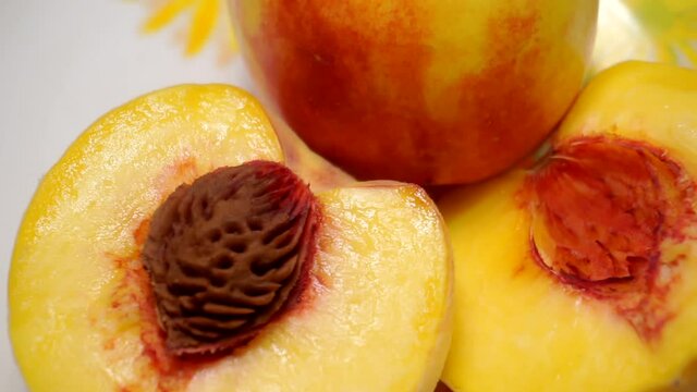 juicy ripe brightly cut peaches rotate on a plate.close-up.