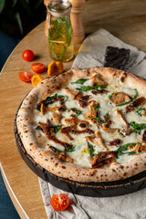 Stove baked pizza with mushrooms and parmesan on wooden table in a fancy restaurant, soft light, posh photography