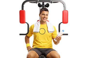Naklejka premium Portrait of a smiling man on a fitness machine holding a bottle of water