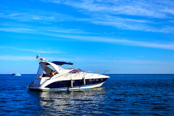 Touristic white motorboat in the sea against blue sky with spindrift clouds. Seascape. Local tourism. Black sea