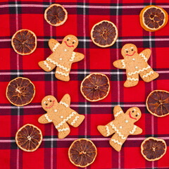 Gingerbread men with dried orange slices on a red tartan background. Top view.