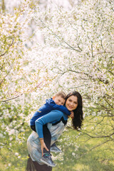 Mother and son play and have a fun in blooming garden.