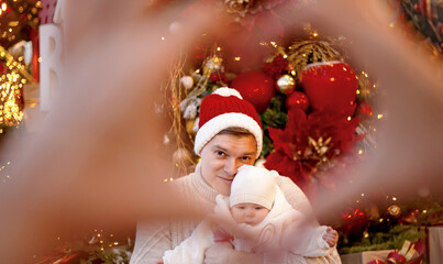 Happy man holding the baby and posing in the decoration of christmas holiday
