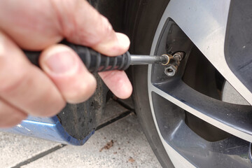 A modern car tyre being inflated on a garage service station forecourt with compressed air tyre pump