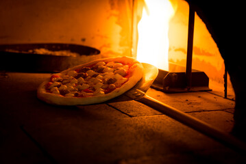 Close-up shot of hand made traditional italian pizza in wood fire oven 