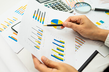 Asian accountant working and analyzing financial reports project accounting with chart graph and...