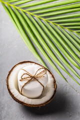 Handmade coconut oil soap white color with palm leaf on grey concrete background.