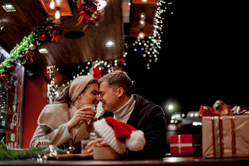 Obraz na płótnie Canvas Couple in love relationship believe in meracle, kissing against the chrismas decoration outdoor in the eve, look at each other and drink the warm drinks