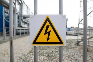 Sign of High Voltage on the street panel of electrical equipment. Danger warning symbol. Industrial background.