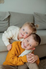 Fototapeta na wymiar Little brother and sister in cozy knitted sweaters play at home. Portrait of cute little brother and sister. Fall.