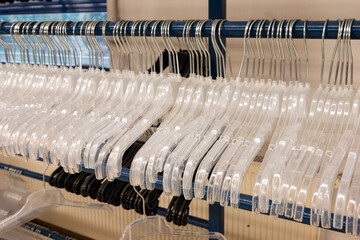 Fototapeta premium Row of white transparent plastic coat hangers hanging on a metal pole inside factory ready for use