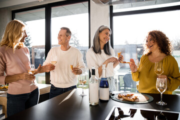 Happy adult women and man enjoying wine at home