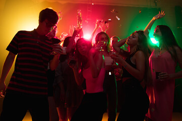 Cocktail. A crowd of people in silhouette raises their hands, dancing on dancefloor on neon light background. Night life, club, music, dance, motion, youth. Bright colors and moving girls and boys.