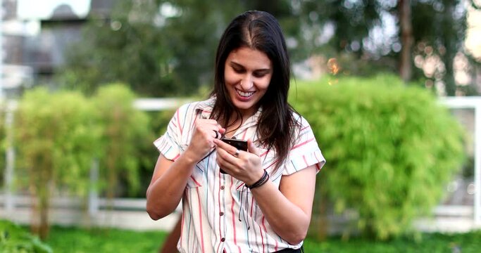Happy young woman celebrates after good news holding cellphone