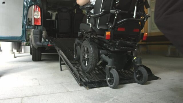 Wheelchair going into vehicle using ramp. Driver is helping to push it up.