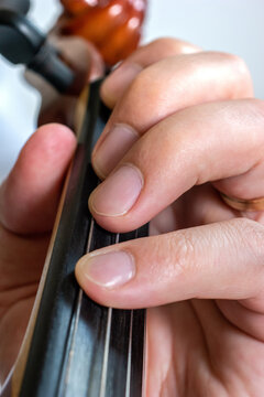 Caucasian young male fingers playing on the violin board and cord macro close up shot