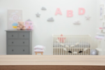 Empty wooden table in baby room. Space for text