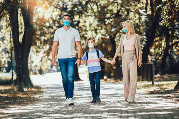 Fototapeta premium Mother,father and little son wearing face protective medical mask for protection from virus disease in park.
