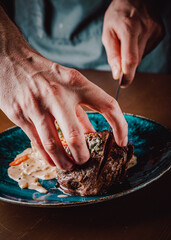 chef hand cut Grilled beef steak filet mignon in plate on wooden table