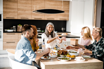 Smiling friends are exchanging gifts during thanksgiving