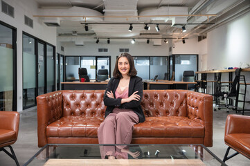 Obraz premium Asian woman entrepreneurs confident sitting and smiling on vintage sofa in coworking space at office