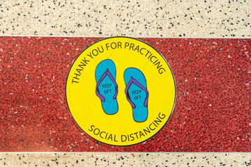 Circular sign on floor requesting social distancing