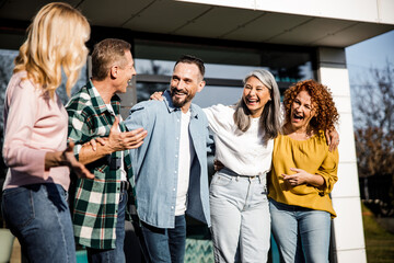Friends are laughing and standing near house