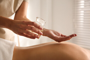 Young woman receiving back massage with oil in spa salon, closeup
