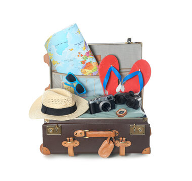 Open vintage suitcase with clothes and beach objects packed for summer vacation isolated on white
