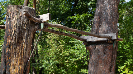 Sports wooden uneven parallel bars are made of  logs.  Attached wooden bars to tree trunks are shown in close-up.
