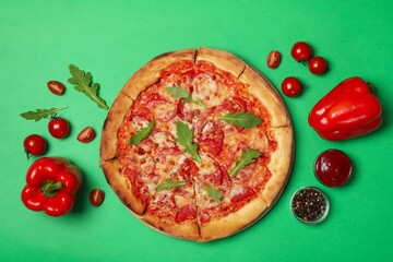 Tasty pizza and ingredients on green background