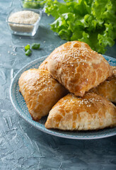 Juicy samsa on a blue plate. Samsa with meat and onions. Samsa sprinkled with sesame seeds.