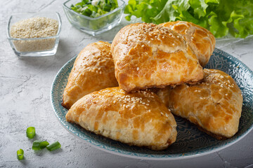 Juicy samsa on a blue plate. Samsa with meat and onions. Samsa sprinkled with sesame seeds.