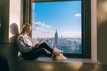 Happy female freelancer checking information while watching streams video via modern touch pad with...