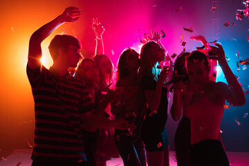 Wild. A crowd of people in silhouette raises their hands, dancing on dancefloor on neon light background. Night life, club, music, dance, motion, youth. Bright colors and moving girls and boys.