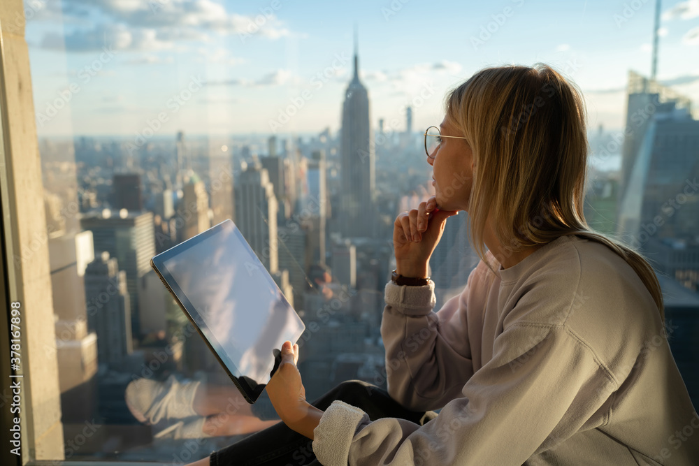 Aufkleber thoughtful female digital nomad with modern touch pad looking in panoramic window while creation soc