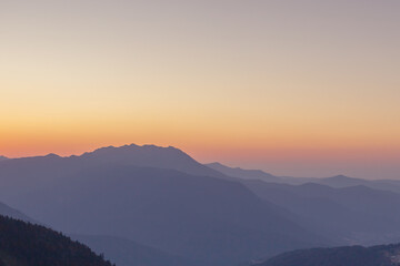 A scenic sunset in the mountains with sunlight, beautiful light. Evening summer landscape in a valley with horizon, sky, grass, flowers. Hiking and trekking.
