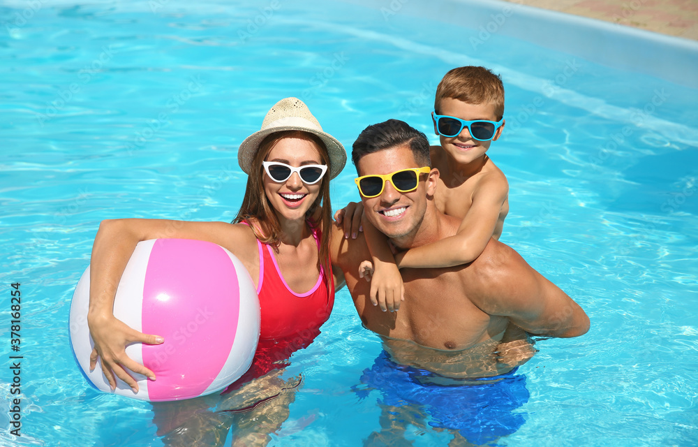 Wall mural happy family in swimming pool on sunny day