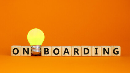 Wooden cubes with word 'onboarding'. Yellow light bulb. Beautiful orange background. Business...